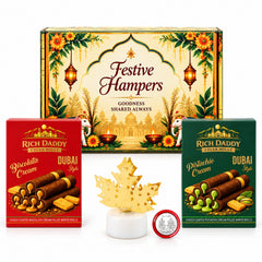 A festive gift hamper with two boxes of wafer rolls, a golden maple leaf lamp, and a silver coin on a white background.
