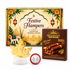 A gift box with traditional Indian motifs, a lit golden maple leaf lamp, and a Rich Daddy hazelnut cream wafer roll box.