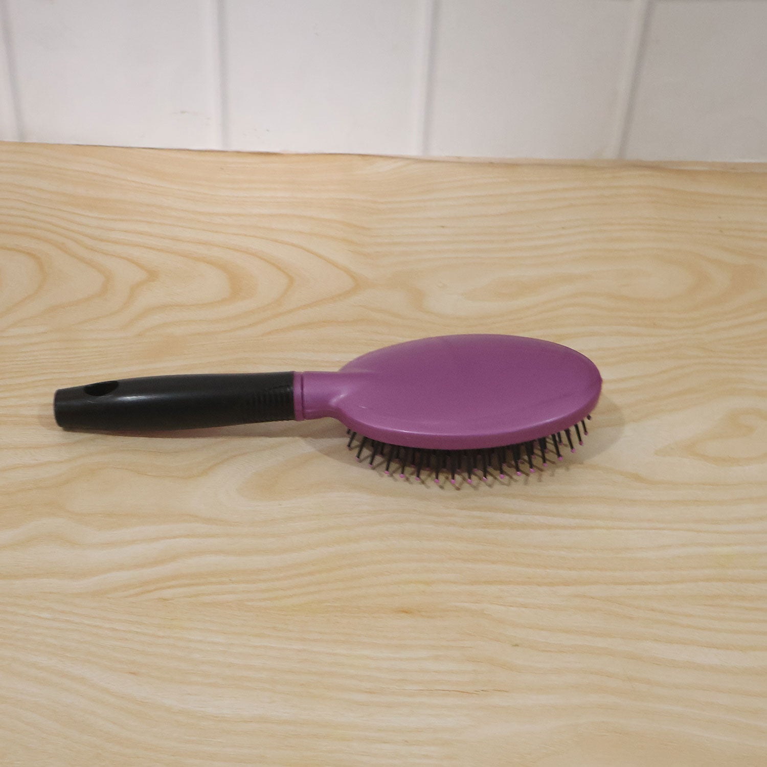 Person brushing hair with cushioned paddle brush