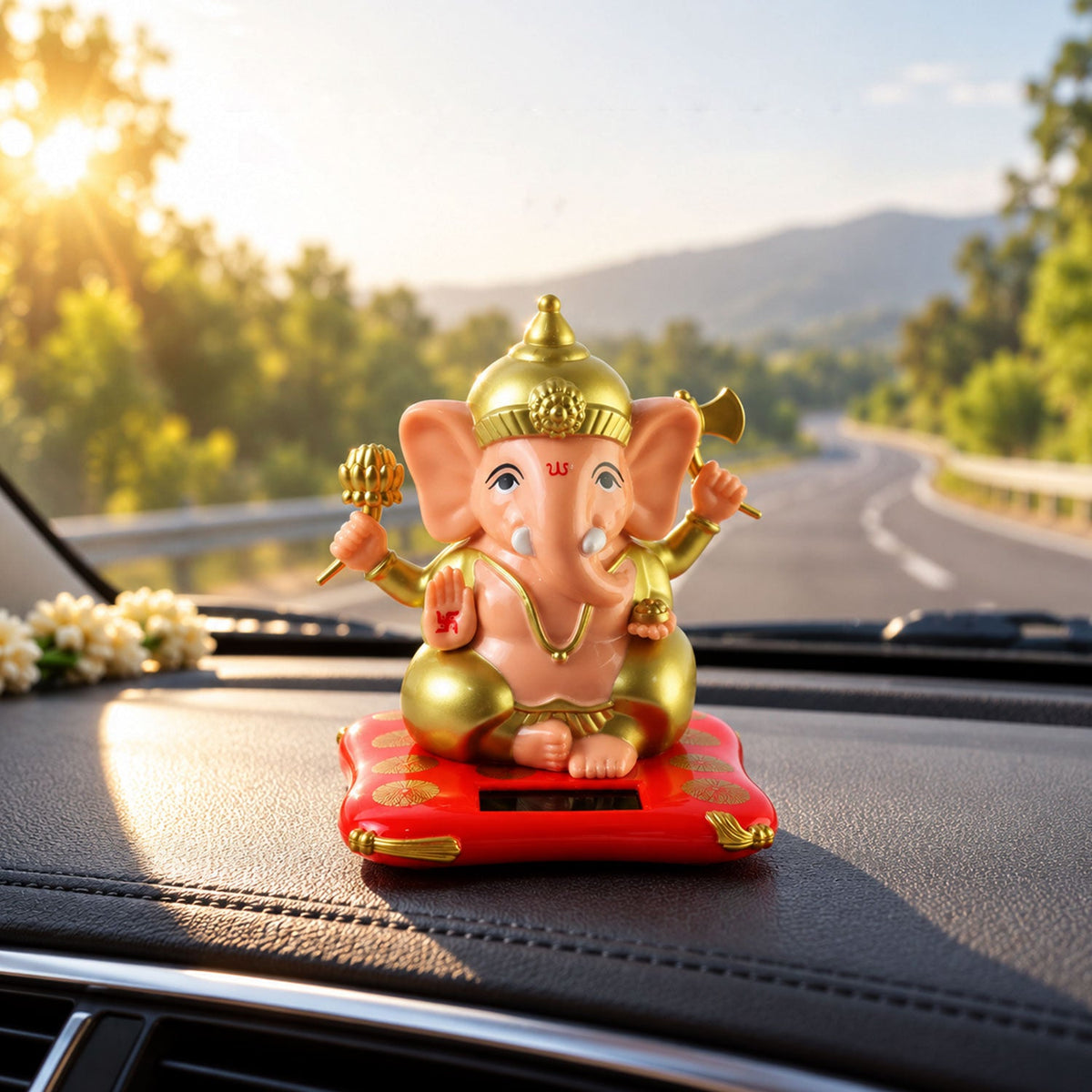 A peach and gold Ganesha idol on a red cushion with a solar panel, sitting on a car dashboard at sunset.