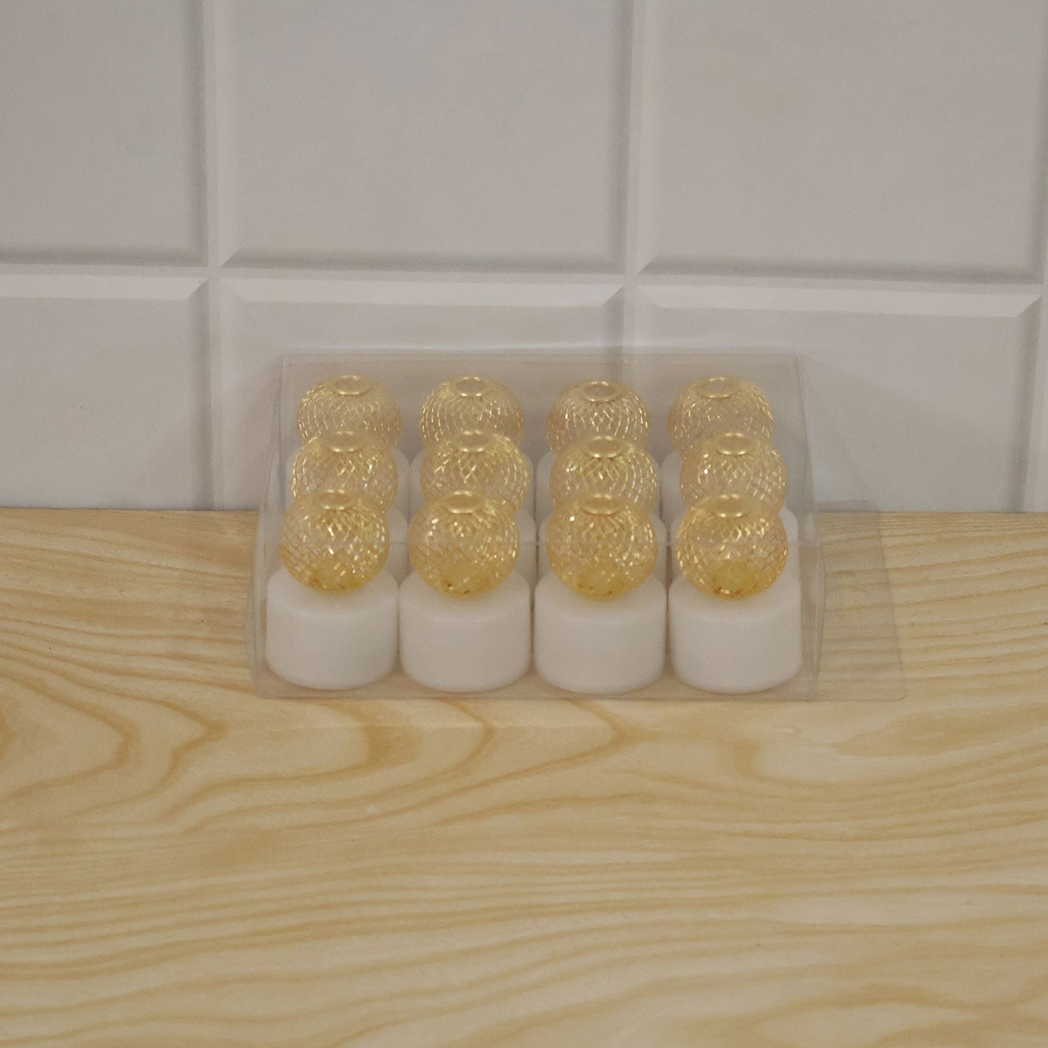Twelve LED tealight candles with gold mesh covers in plastic box packaging