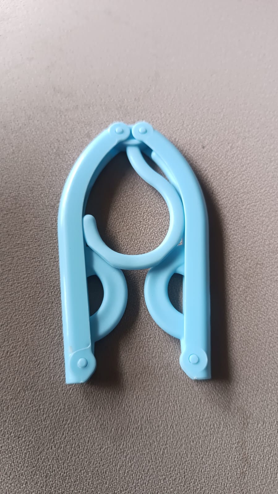 Foldable travel hanger displayed in compact folded position.