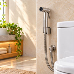 A brushed steel bidet sprayer with a flexible hose is mounted on a tiled wall next to a white toilet in a bright â€“ view 3