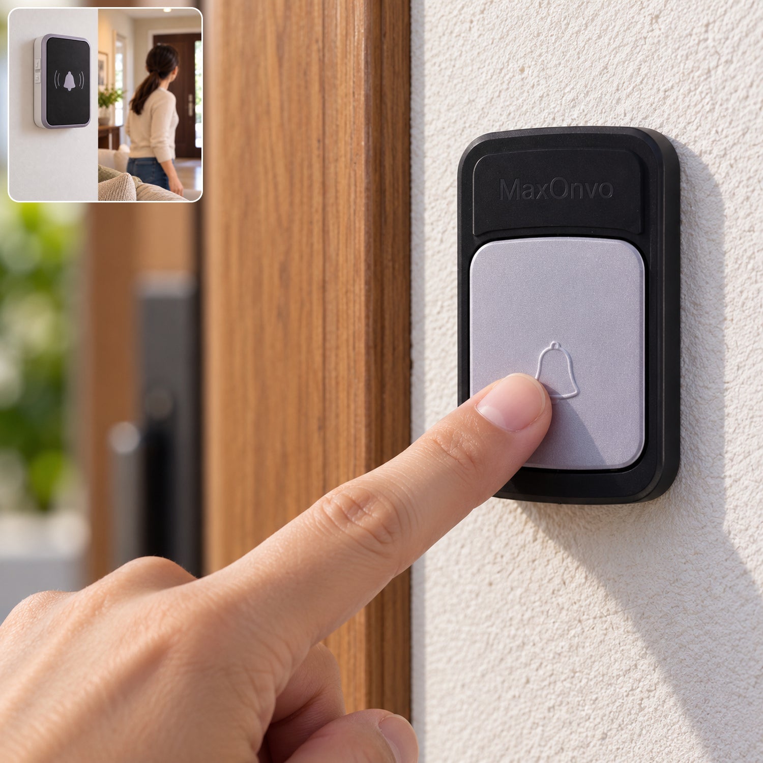 A person's finger presses the light grey button of a black wireless doorbell transmitter on a white wall next to a wooden