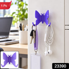 A purple butterfly hook on a white wall, with keys and earphones hanging from its wings.
