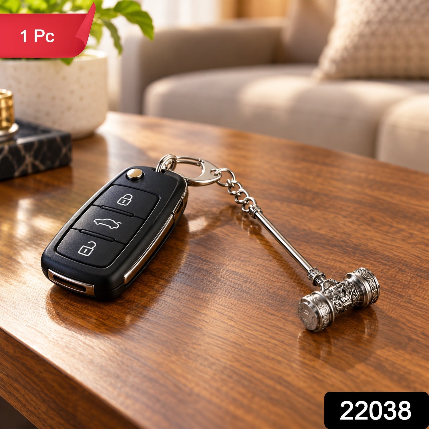Silver-plated hammer keychain attached to a black car remote, resting on a polished wooden table. A green plant and â€“ view 2