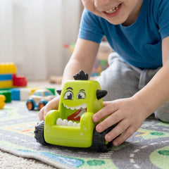 Child's hand pushing a blue friction monster car toy