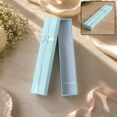 An open light blue rectangular gift box with a light blue ribbon and bow, on a light surface with flowers.