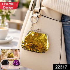 A gold sequined coin purse with a silver kiss-lock clasp and key ring hangs from a cream-colored handbag. â€“ view 2