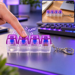 A hand presses a purple and clear four-key keyboard switch keychain, with a smaller inset image showing it on a desk.