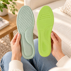 A person holding two shoe insoles: one light green with texture, the other bright lime green with grooves, over their lap.