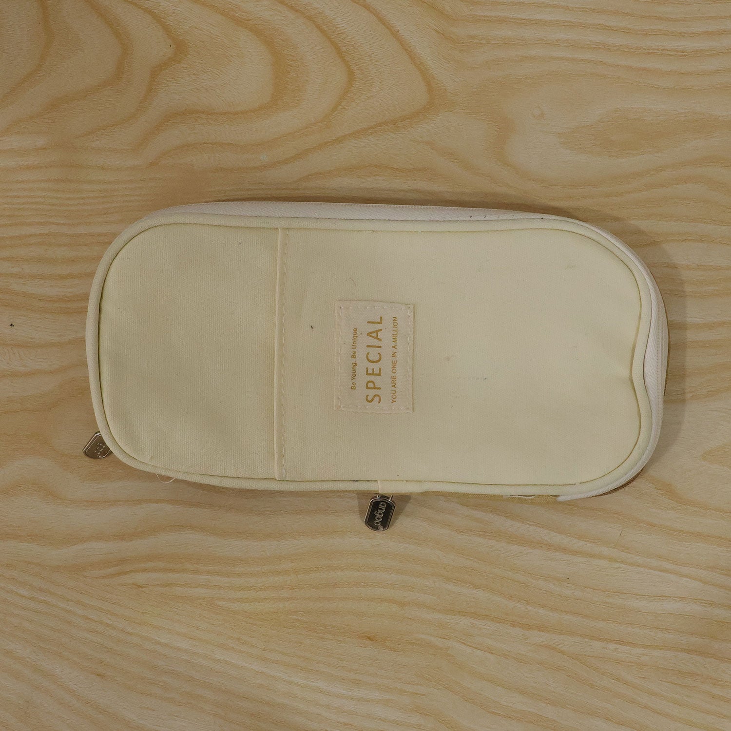 A closed, two-toned beige canvas pencil case with a â€“ view 9