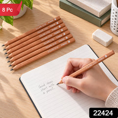 A hand writes in a lined journal with one light brown pencil, while seven identical pencils lie nearby on a wooden desk.