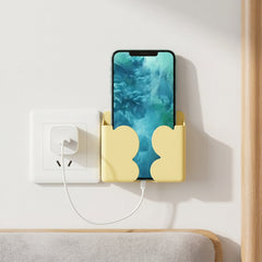 A smartphone securely held in the wall mount phone holder next to a power socket.