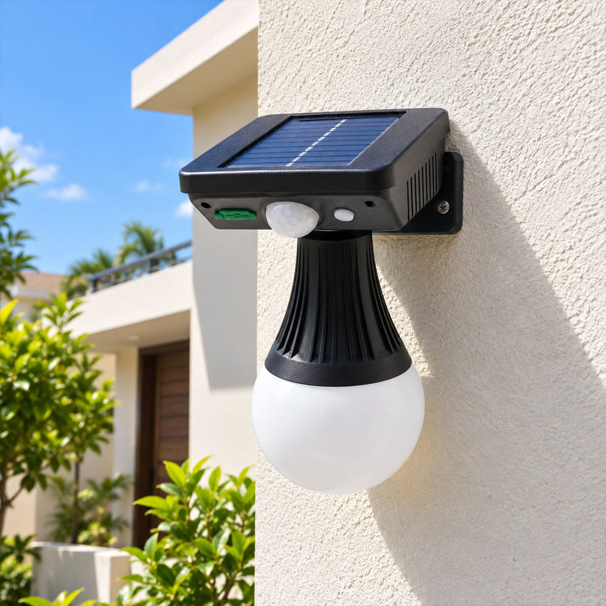 Black solar motion sensor light with a white globe bulb attached to a cream wall outdoors.
