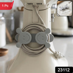 A gray silicone cord organizer with two smiling faces, holding a coiled light gray appliance cord on a white stand mixer,