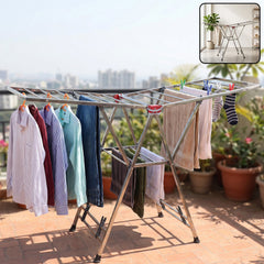 A stainless steel clothes drying rack with various garments hanging on it, set on an outdoor patio with city views.