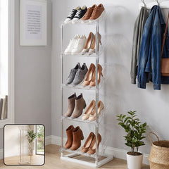 A tall, five-tier shoe rack with clear slanted shelves holds various shoes in a bright room.
