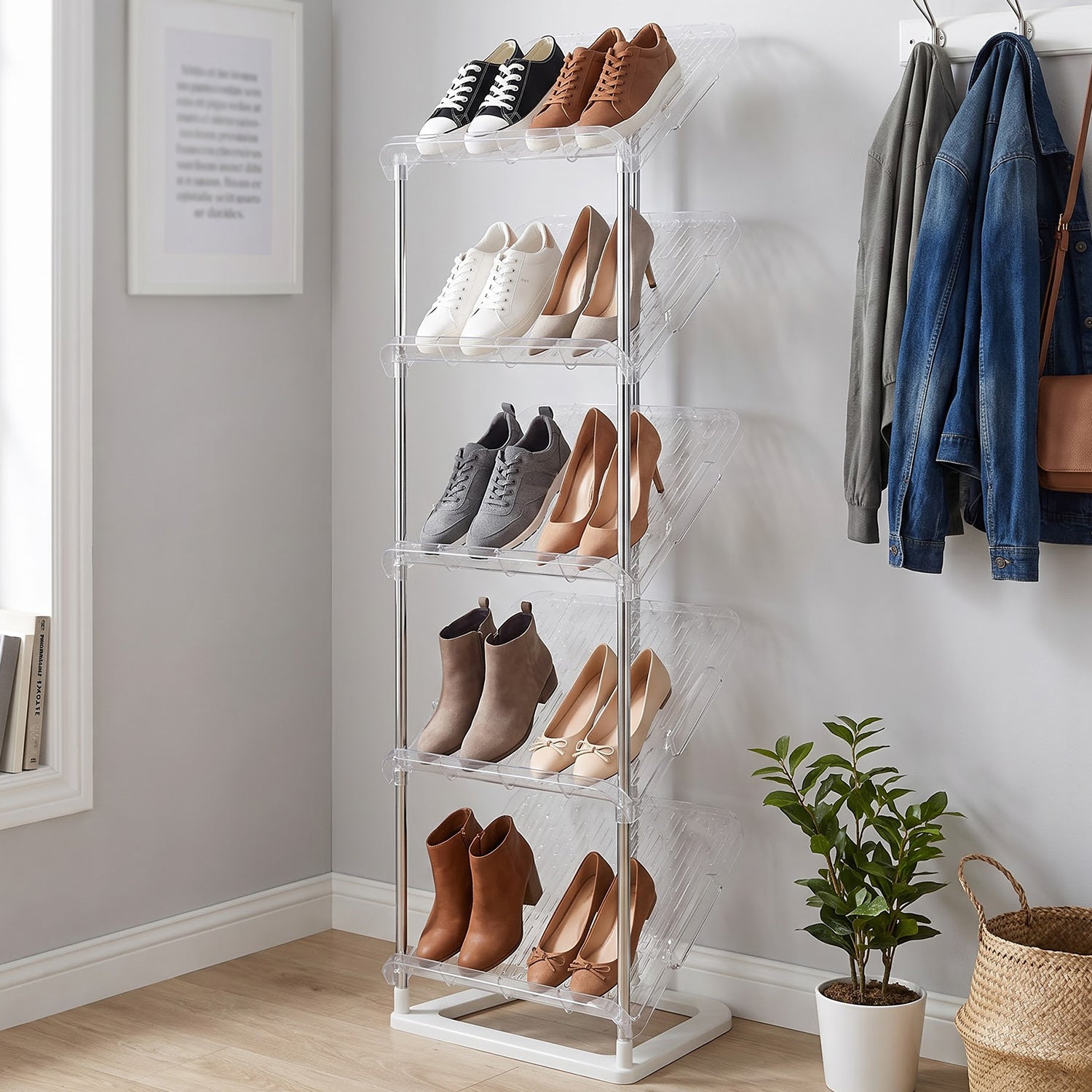 A shoe rack featuring five transparent, angled shelves filled with diverse shoes, positioned by a window.