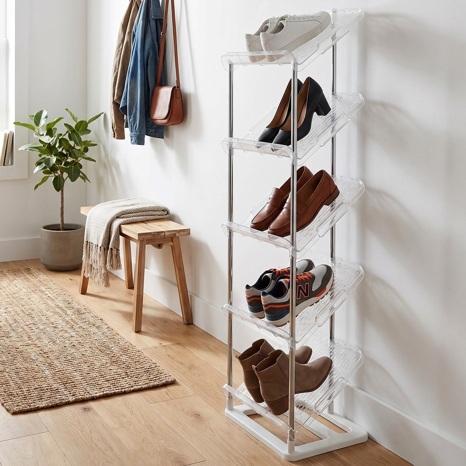 A five-tier shoe rack with clear shelves displaying various shoes, situated in a modern entryway with a bench.