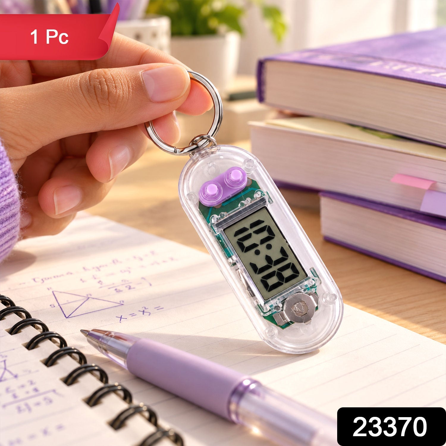 A person's hand holds a transparent digital clock keychain above a spiral notebook with a purple pen.