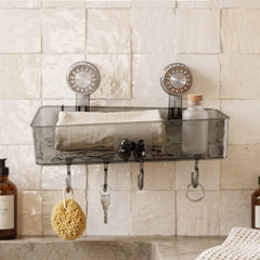 A clear grey plastic caddy with four hooks is mounted on a textured white wall, holding a sponge, keys, and a small bottle.