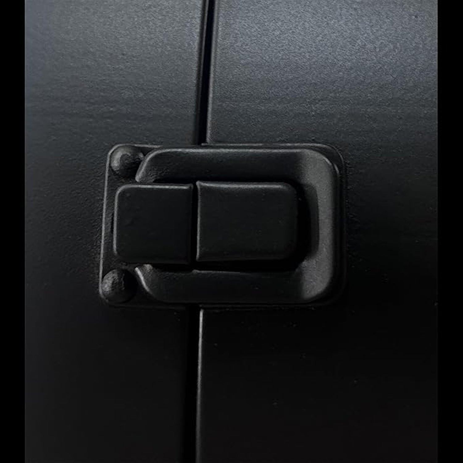 A close-up shot of the black metal latch mechanism on the side of the double-sided clock, showing its textured surface and