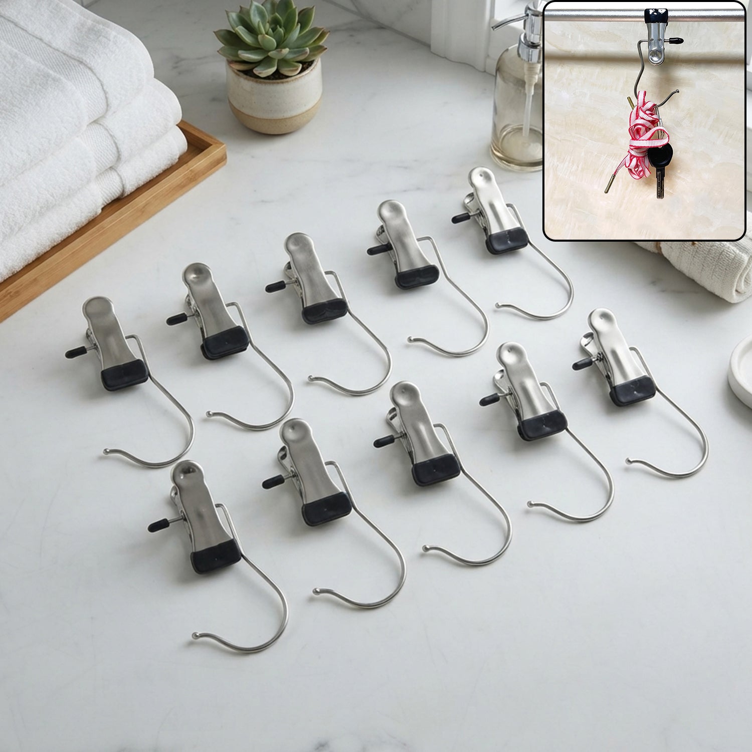 Ten metal clip hangers with black rubber tips are neatly arranged on a white marble countertop next to folded towels