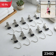 Ten metal clip hangers with black rubber tips are neatly arranged on a white marble countertop next to folded white towels