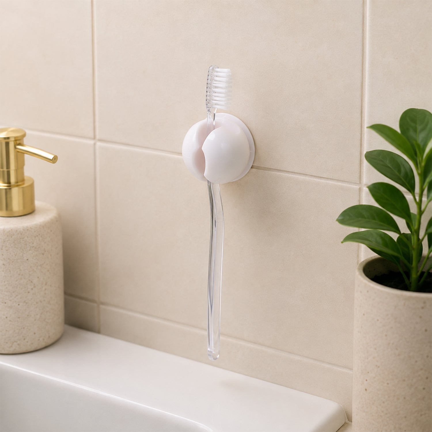 A white toothbrush holder clip on a tiled wall, holding a clear toothbrush above a sink, with a soap dispenser and â€“ view 8