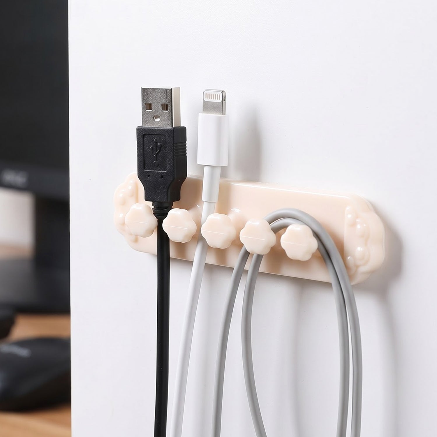 A beige self-adhesive cable organizer clip with five flower-shaped holders, securing black, white, and gray USB â€“ view 3