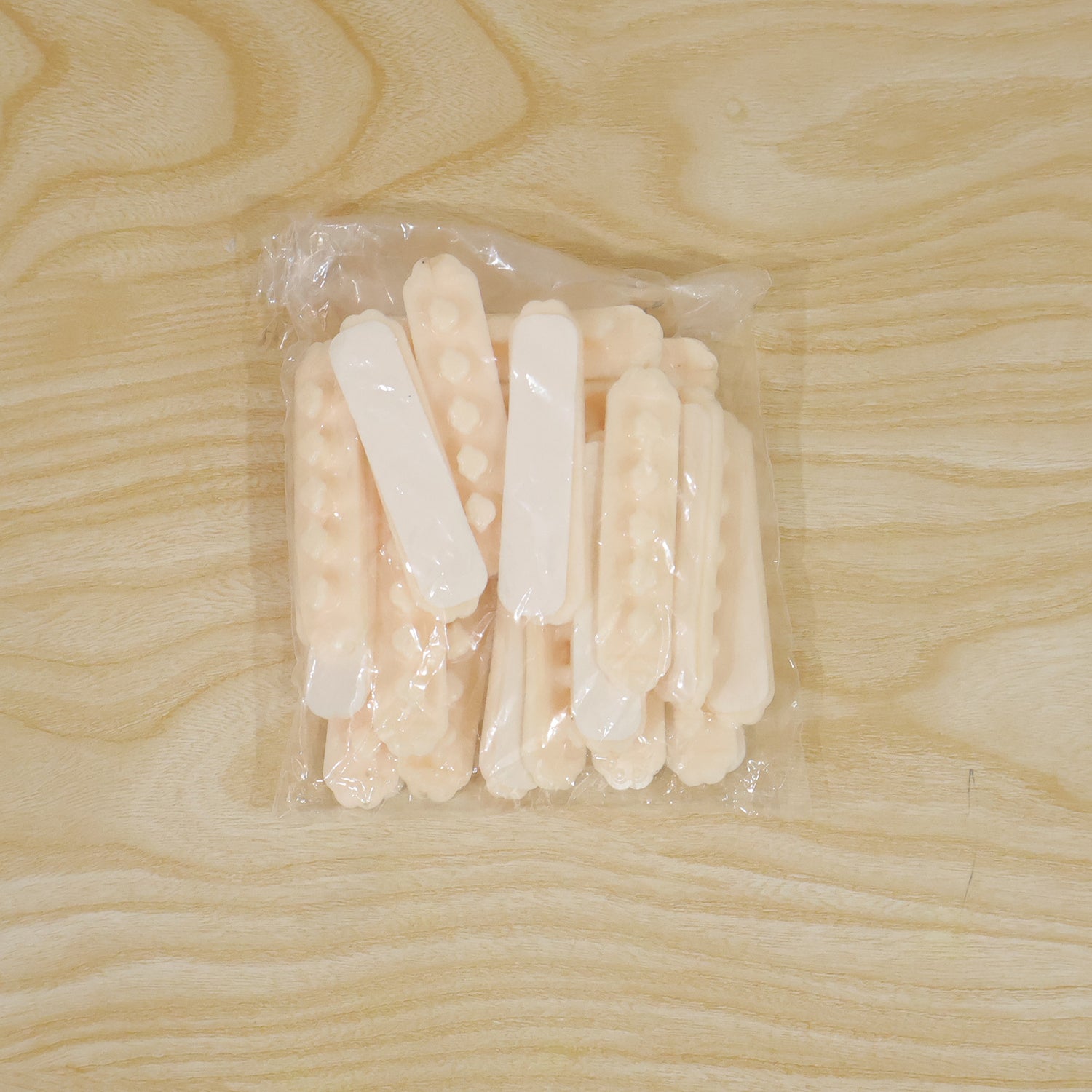 A clear plastic bag filled with multiple beige self-adhesive cable organizer clips, each with five flower-shaped holders, on