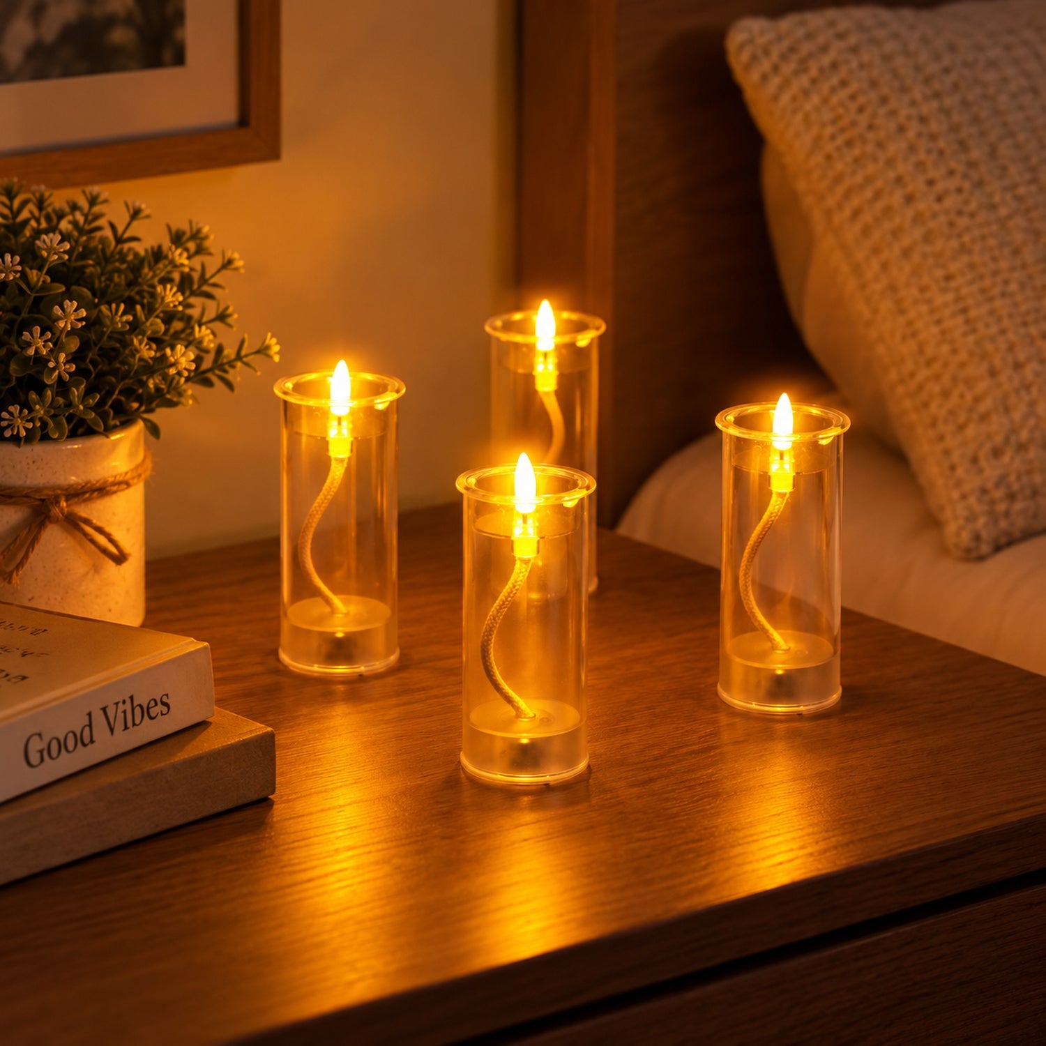 Four LED swing candles illuminate a wooden bedside table, next to a small potted plant and a book titled "Good Vibes".