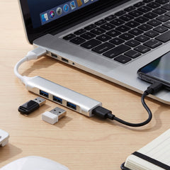 Silver 4-port USB hub connected to a laptop, with two USB drives plugged in