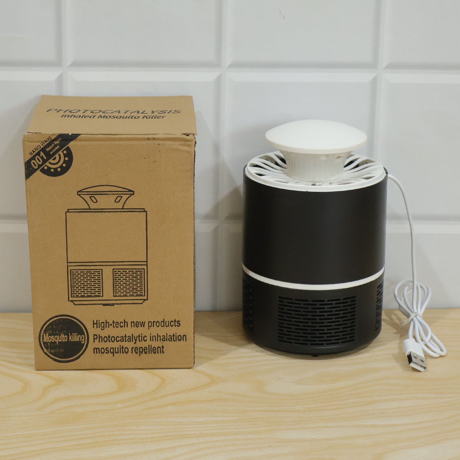 Black and white mosquito killer lamp next to its brown cardboard packaging on a wooden surface.