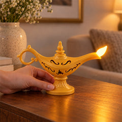 A hand holds a glowing yellow Aladdin's lamp LED light on a wooden table, with a floral vase in the background.