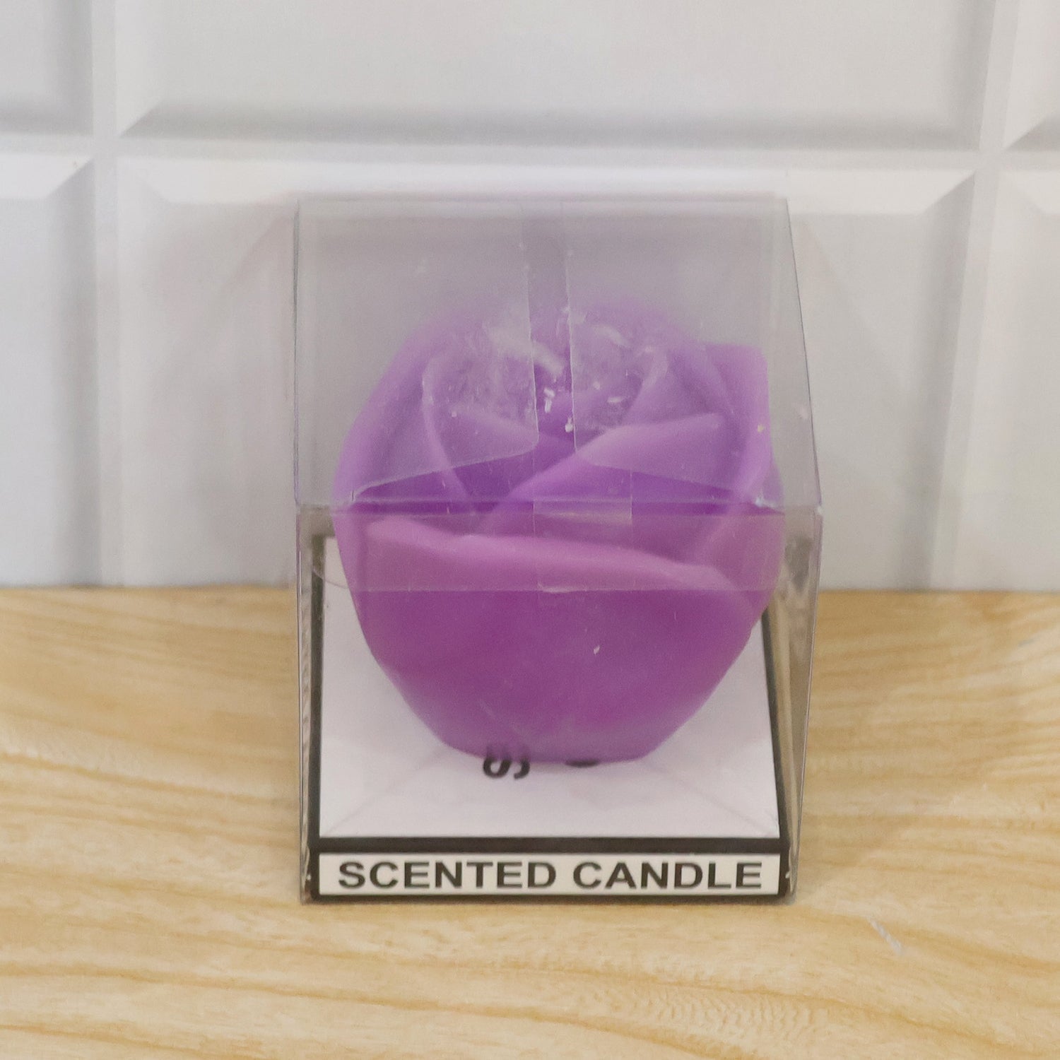 A purple rose-shaped candle is packaged in a clear plastic box with a label that says "SCENTED CANDLE".