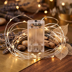 Warm white LED string lights coiled around a clear battery box, surrounded by dried lavender and decorative rocks.