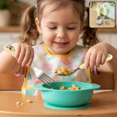 A young girl in a bib holds a panda-handled fork and spoon, eating pasta from a teal bowl.