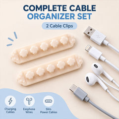 Two beige flower-shaped cable organizer clips and various cables (USB, Lightning, USB-C, earphones) on a light blue surface.