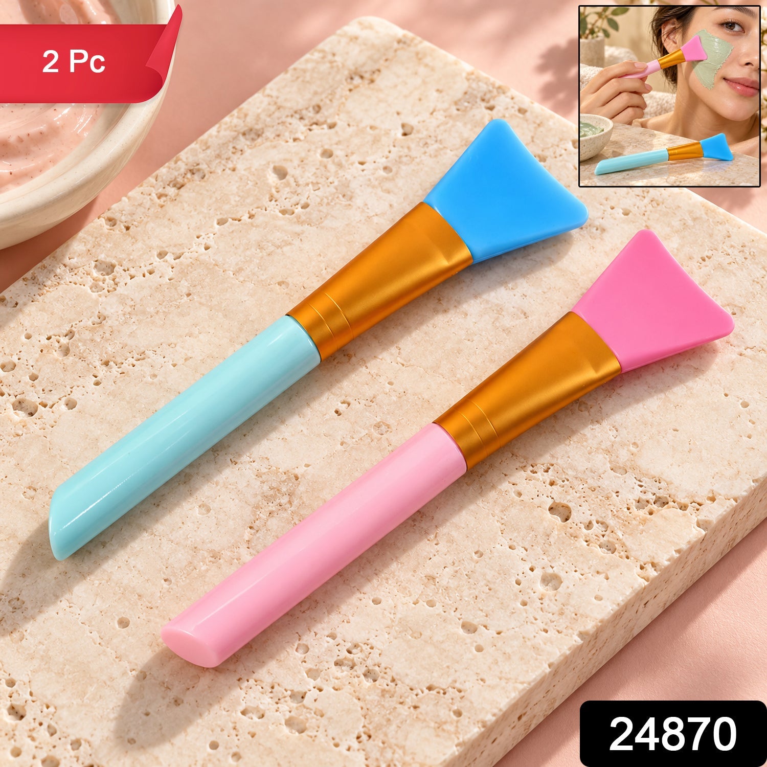 Two silicone face mask brushes, one pink and one blue, rest on a light marble surface with a small inset image of a woman