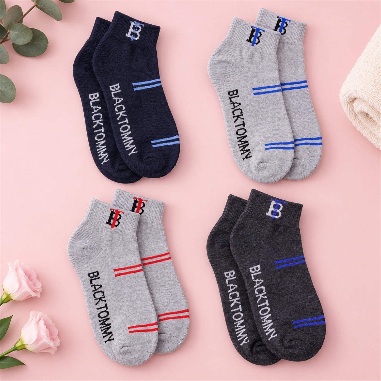 Four pairs of ankle socks in navy, grey, and charcoal, each with unique stripe and text colors, on a pink surface.