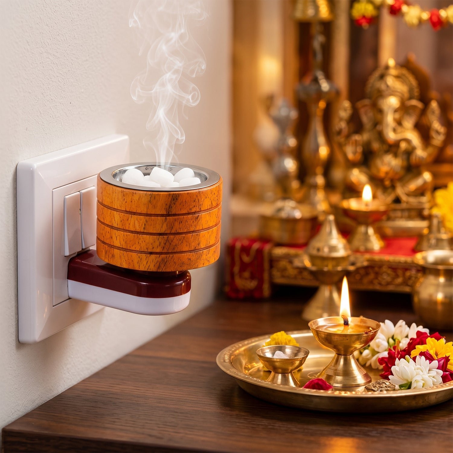 A wooden electric camphor diffuser plugged into a wall socket emits smoke, beside a lit lamp and flowers.