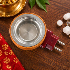 Overhead view of a round wooden diffuser with a silver metal cup, next to a red fabric and camphor pieces.
