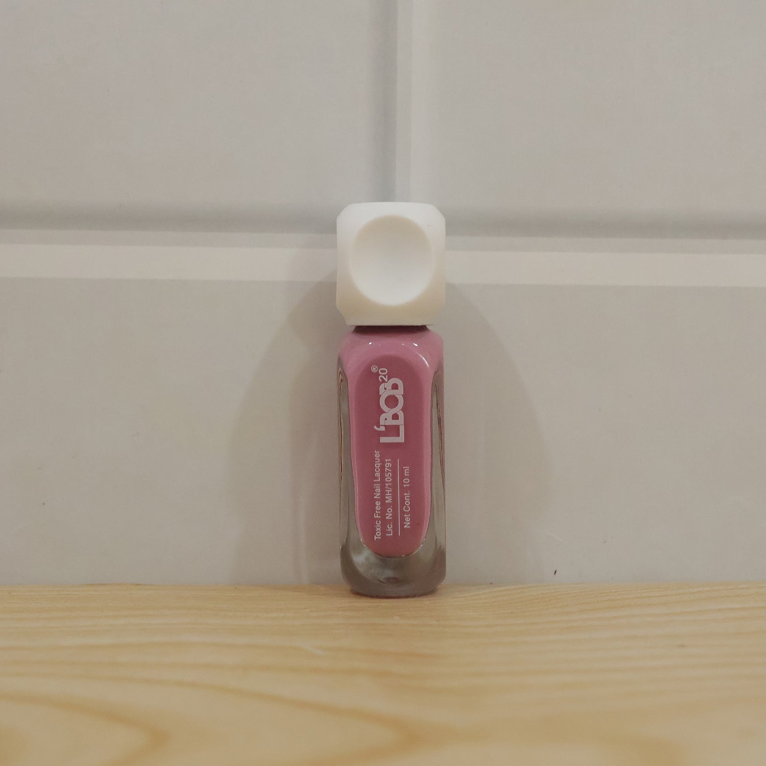Pink Nude Colour Nail Polish bottle with painted nails in background