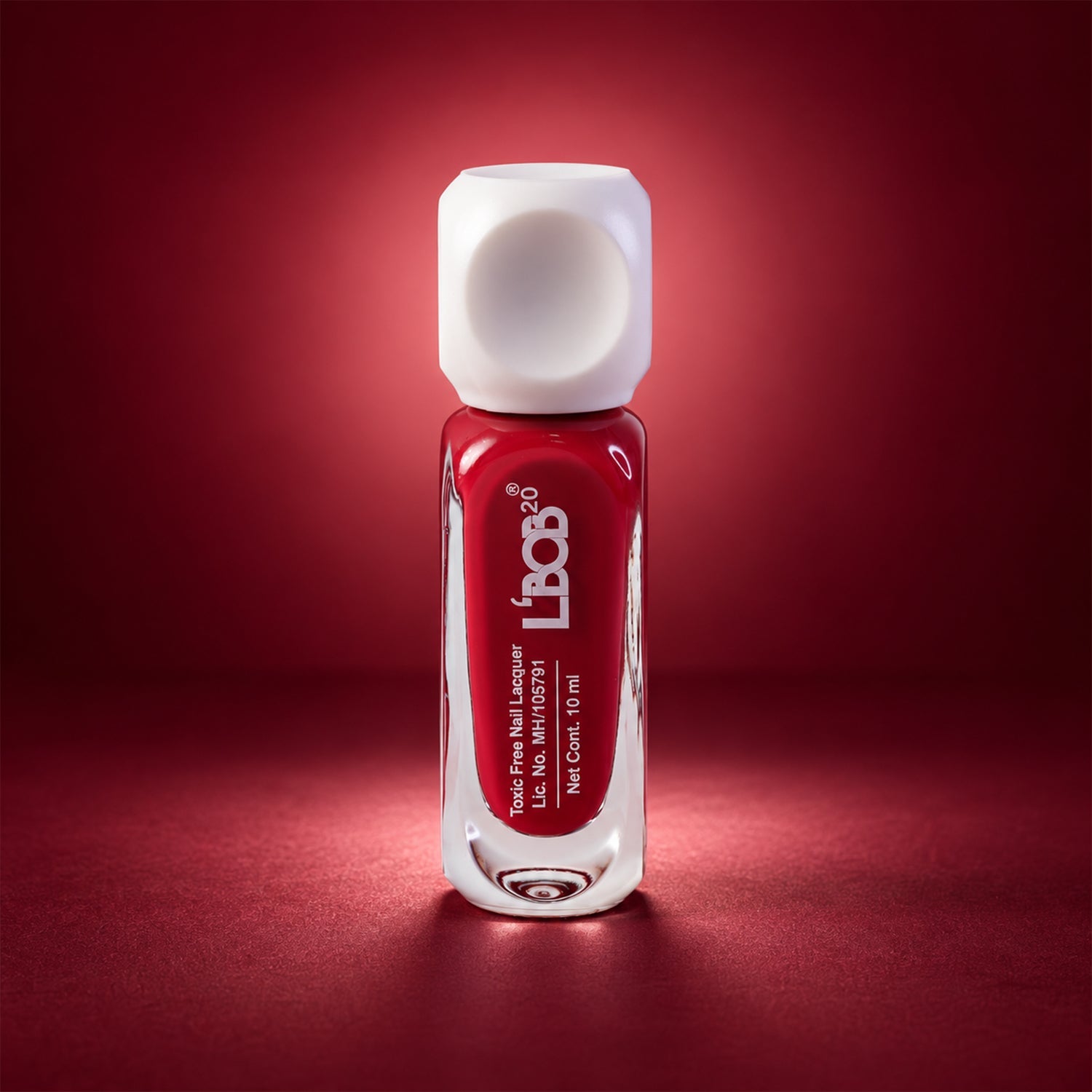 A single bottle of red nail polish with a white cap stands centered against a dark red gradient background.