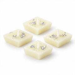 Four unlit diamond-shaped cream candles with silver foil accents are neatly arranged on a plain white background.