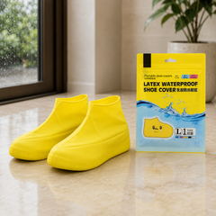 A pair of bright yellow latex shoe covers and their matching yellow and blue packaging stand on a tiled floor.