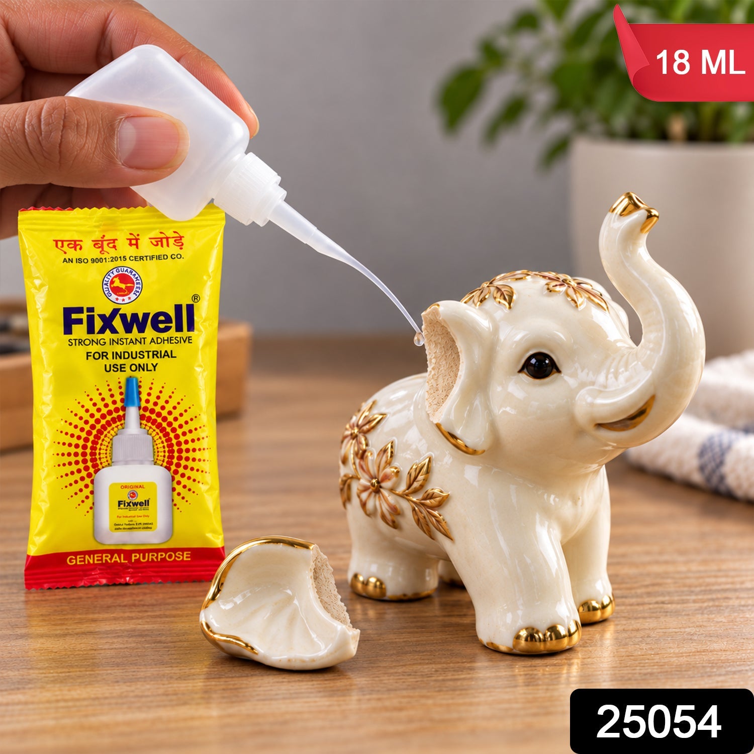 A hand applies glue from a white bottle with a fine nozzle to repair a broken ceramic elephant figurine. â€“ view 2