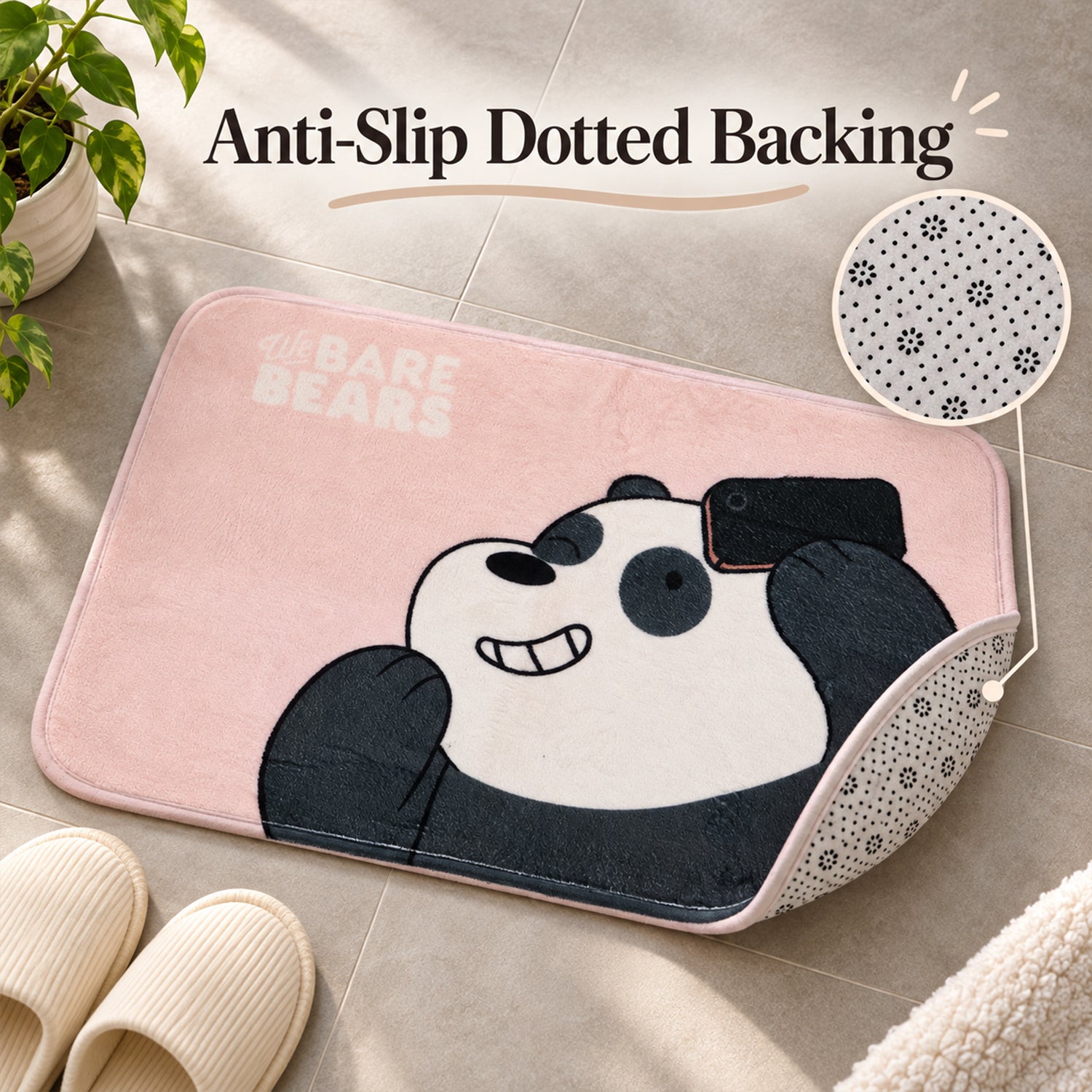 A pink panda mat with a corner lifted to reveal a dotted anti-slip backing, next to slippers on a tiled floor.